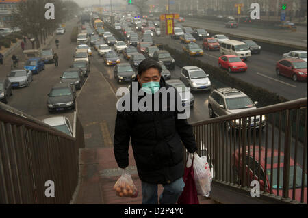 A man wearing a mask past heavy traffic in thick haze in Beijing,  China. 30-Jan-2013 Stock Photo