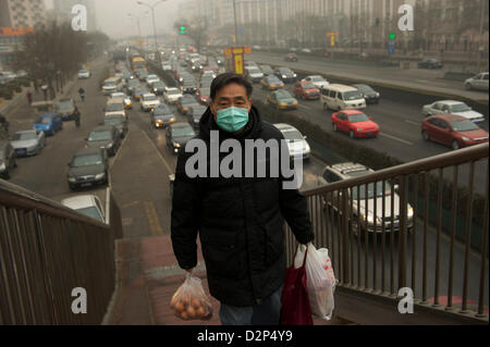 A man wears a mask past heavy traffic in thick haze in Beijing,  China. 30-Jan-2013 Stock Photo