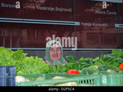 A vegetable seller in front of memorial wall to those who were killed and injured during 1994 Markale marketplace massacre. Stock Photo