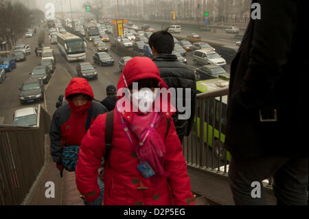 A girl wears a mask past heavy traffic in thick haze in Beijing, China. 30- Jan-2013 Stock Photo