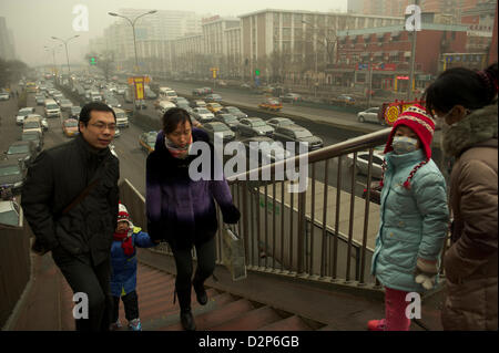 Pedestrians walk on an overpass past heavy traffic in thick haze in Beijing,  China. 30-Jan-2013 Stock Photo