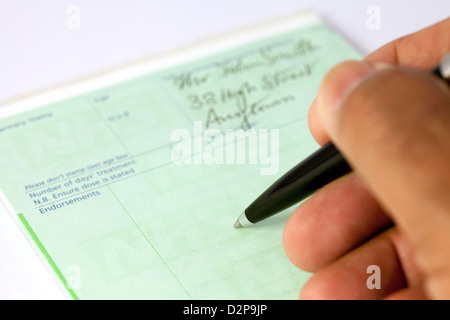 A doctor writing a prescription form for medication on his prescription pad for a patient in the NHS, UK Stock Photo