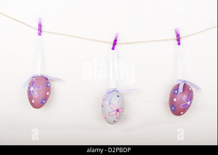 Purple Easter eggs hanging on a rope on clothespins, wooden background Stock Photo