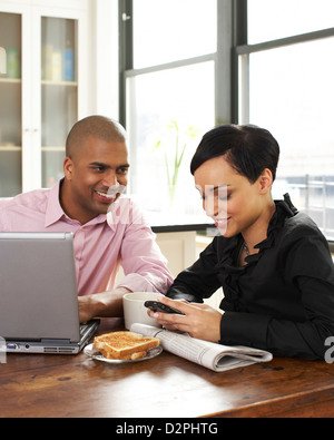 Couple eating breakfast and using laptop and cell phone Stock Photo