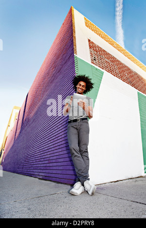 Man using digital tablet and leaning on wall outdoors Stock Photo