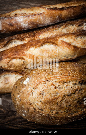 Fresh baked rustic bread loaves on dark wood background Stock Photo