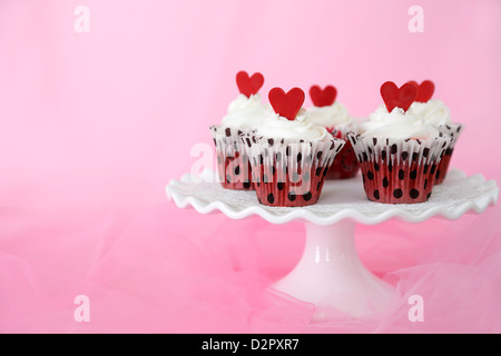 Red velvet cupcakes with cream cheese frosting decorated with red chocolate hearts. Copy space on the side. Stock Photo