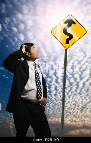 Businessman looking at a Zig Zag Road sign Stock Photo