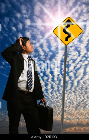 Businessman looking at a Zig Zag Road sign Stock Photo