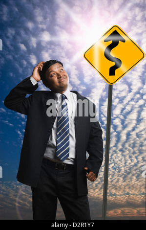 Businessman looking at a Zig Zag Road sign Stock Photo