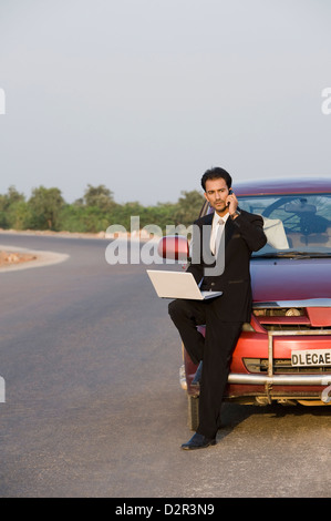 Businessman talking on the phone while using a laptop Stock Photo