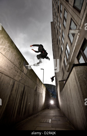 Parkour runners in suits jumping urban alleyway Stock Photo