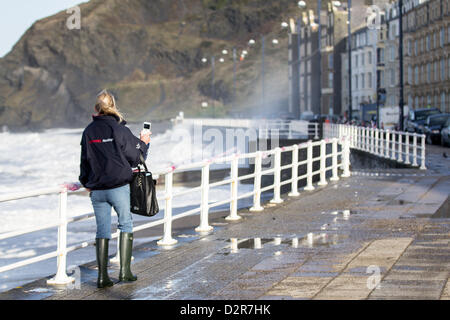 31 January 2013, Aberystwyth, Wales, UK.  A visitor  takes pictures on her mobile phone, as spectacular waves caused by high winds and a high tide lash Aberystwyth promenade. Stock Photo