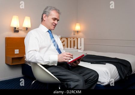 Business man in hotel room using tablet computer. Stock Photo