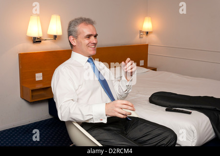 Middle aged business man watching television in a hotel room. Stock Photo