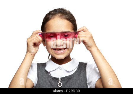 8 year old school girl with pink ruler over her eyes smiling on white background Stock Photo