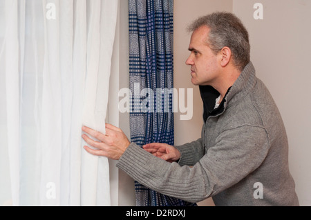 Man looking out of window while isolating alone inside. Stock Photo