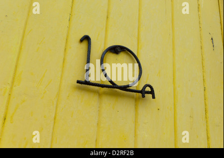Wrought iron house number made from rebar on yellow gate Stock Photo