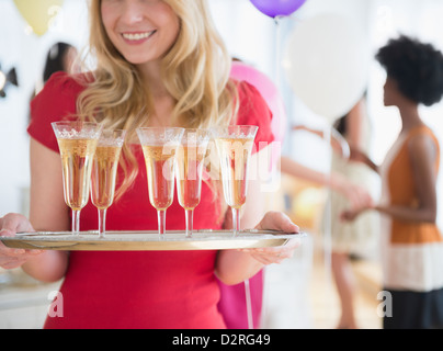Smiling woman carrying tray of champagne Stock Photo