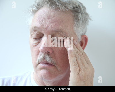 senior rubs the corner of his eye Stock Photo