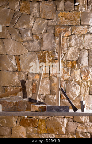 Hammer mason tools of stonecutter masonry work in a contruction stone wall Stock Photo