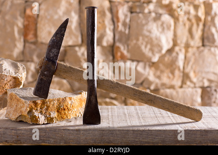 Hammer mason tools of stonecutter masonry work in a contruction stone wall Stock Photo