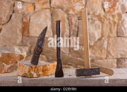 Hammer mason tools of stonecutter masonry work in a contruction stone wall Stock Photo