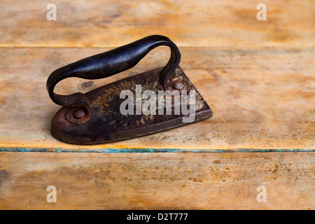 Aged vintage clothes iron in rusted metal over retro wood background Stock Photo