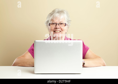 Senior woman using laptop whilst smiling Stock Photo