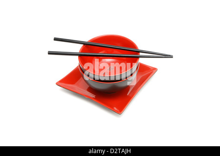 Black chopsticks on two red and black Japanese bowls and square plate isolated Stock Photo