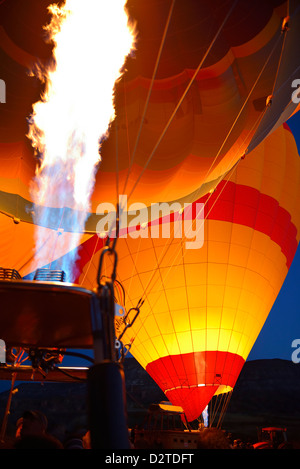 Red glow of blasts from propane heaters inflating hot air balloons at dawn Cappadocia Turkey Stock Photo