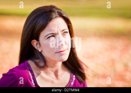Sad beautiful woman outdoors against fall leaf background Stock Photo