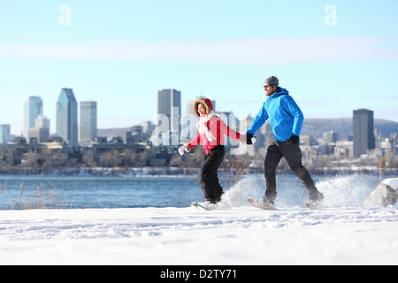 Happy couple snowshoeing in Montreal with cityscape skyline and river st. Lawrence in background Stock Photo