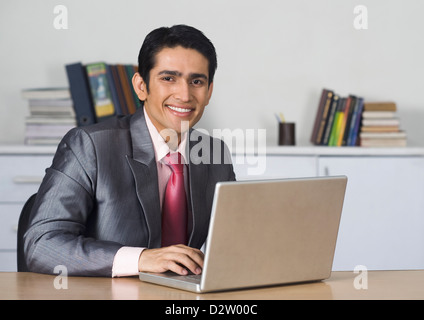 Businessman using a laptop and smiling in an office Stock Photo