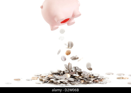 Coins dropping off from piggy bank Stock Photo