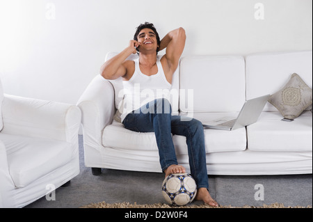 Man talking on a mobile phone on a couch Stock Photo