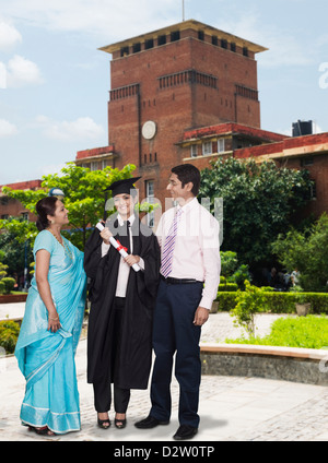 Woman standing with her parents and holding her diploma Stock Photo