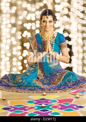 Woman greeting in prayer position near rangoli at Diwali festival Stock Photo