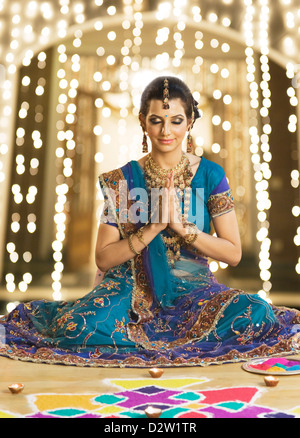 Woman in prayer position near rangoli at Diwali festival Stock Photo