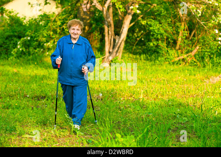 Active old woman (85 years old) nordic walking outdoors. Stock Photo