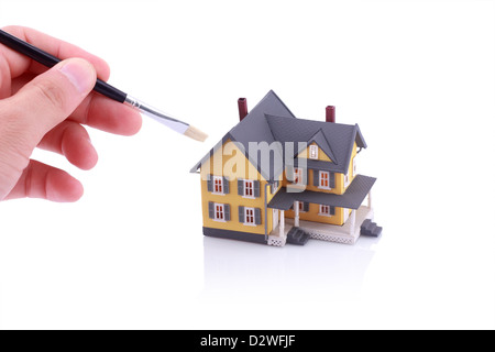 Hand holding brush for painting miniature house Stock Photo