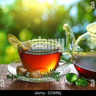 Cup of tea and teapot on a blurred background of nature. Stock Photo