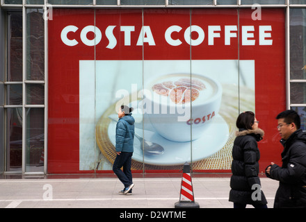 Pedestrian walk past Costa Coffee billboard in Beijing, China. 11-Jan-2013 Stock Photo