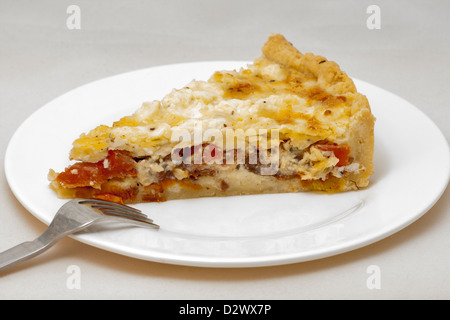 A piece of cheese pie with dried tomatoes on white plate Stock Photo
