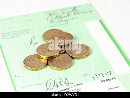 Pound coins on a prescription pad - concept image of prescription charges in the NHS, UK Stock Photo