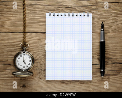 Pocket watch, fountain pen and note book on old wooden background Stock Photo