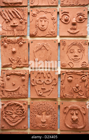 Terracotta tiles with faces on on wall at Romsey, Hampshire, UK in August Stock Photo