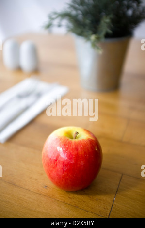 Shiny glossy red apple on a table in a restaurant or dining setting Stock Photo