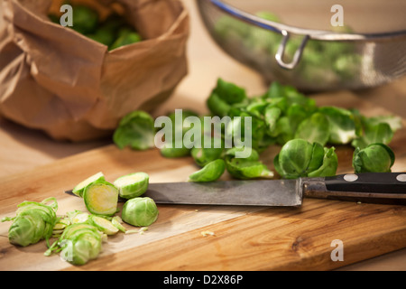 Brussel sprouts on a cutting board. Some of the sprouts are sliced with a knife. Stock Photo