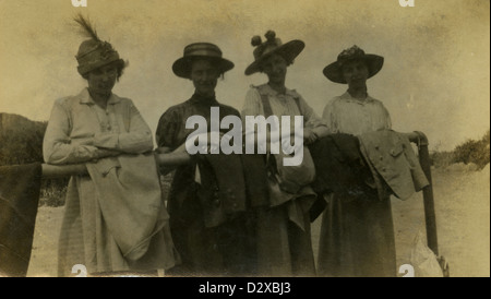 Circa 1910s photograph, four women in period dress leaning on a hitching post or rail. Stock Photo